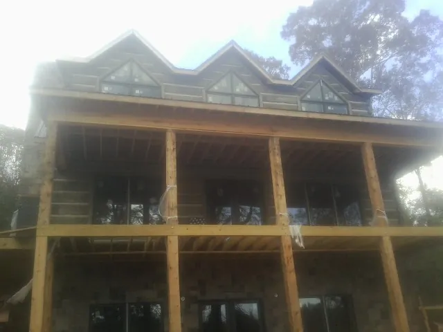 Dormers and porch framing on a large log home under construction — Roof Coating work by our crew in Silver Creek