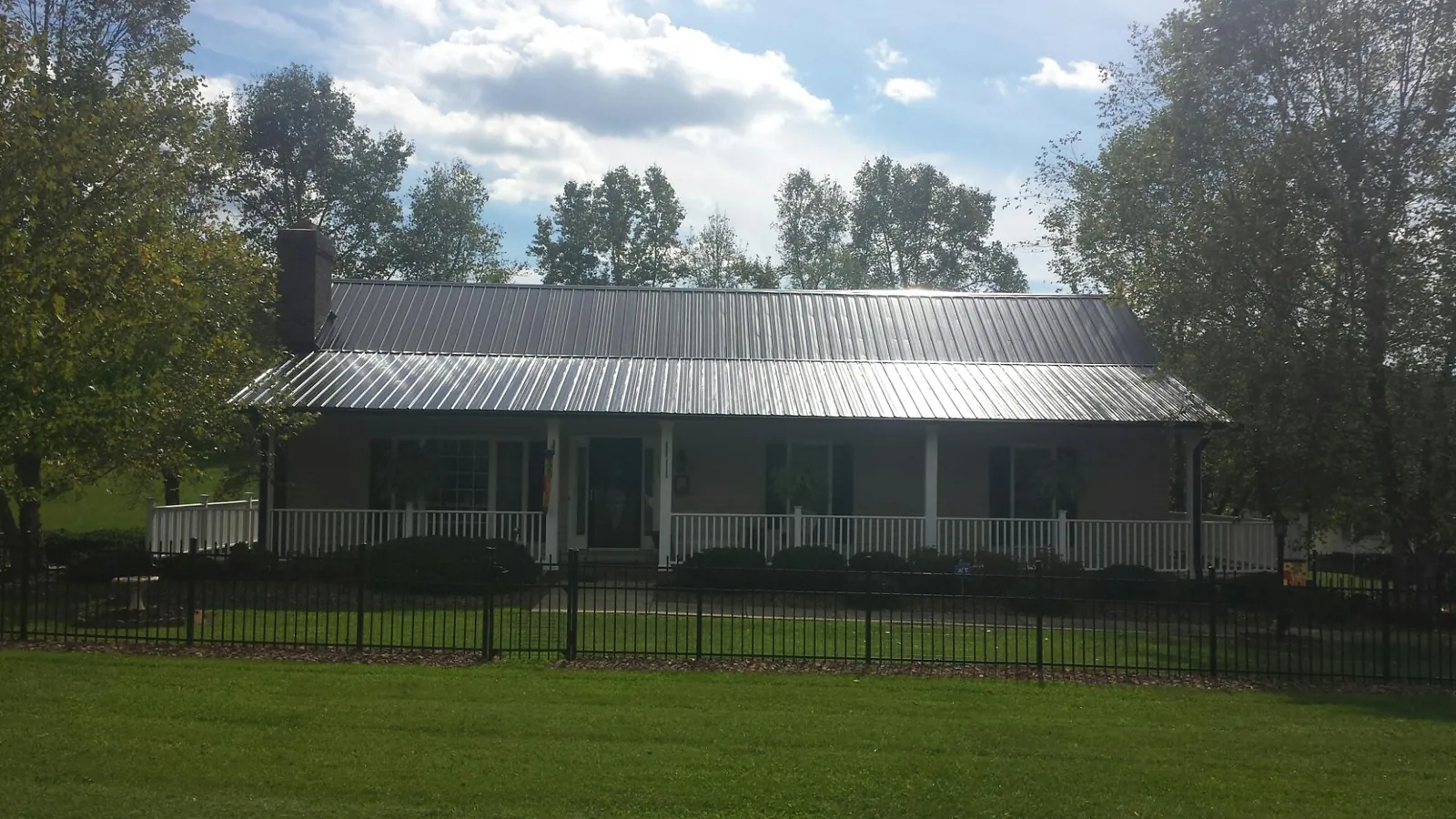 Gray metal roof on a brick ranch with a full width front porch — Gutter Guard Installation work by our crew in Silver Creek