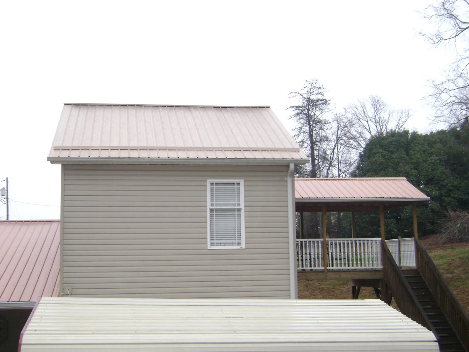 Tan metal roofs on a two story addition and attached porch, from a Roof Replacement job in Silver Creek