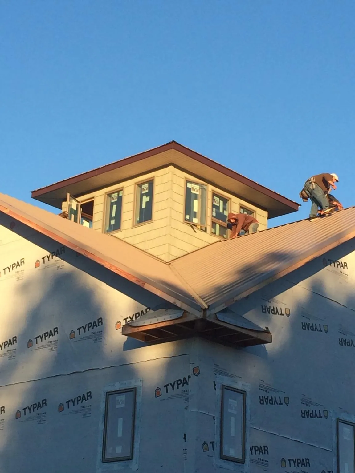 Roofers working around a rooftop cupola on a new metal roof at sunset — Roof Waterproofing in Silver Creek by Roofing Brothers
